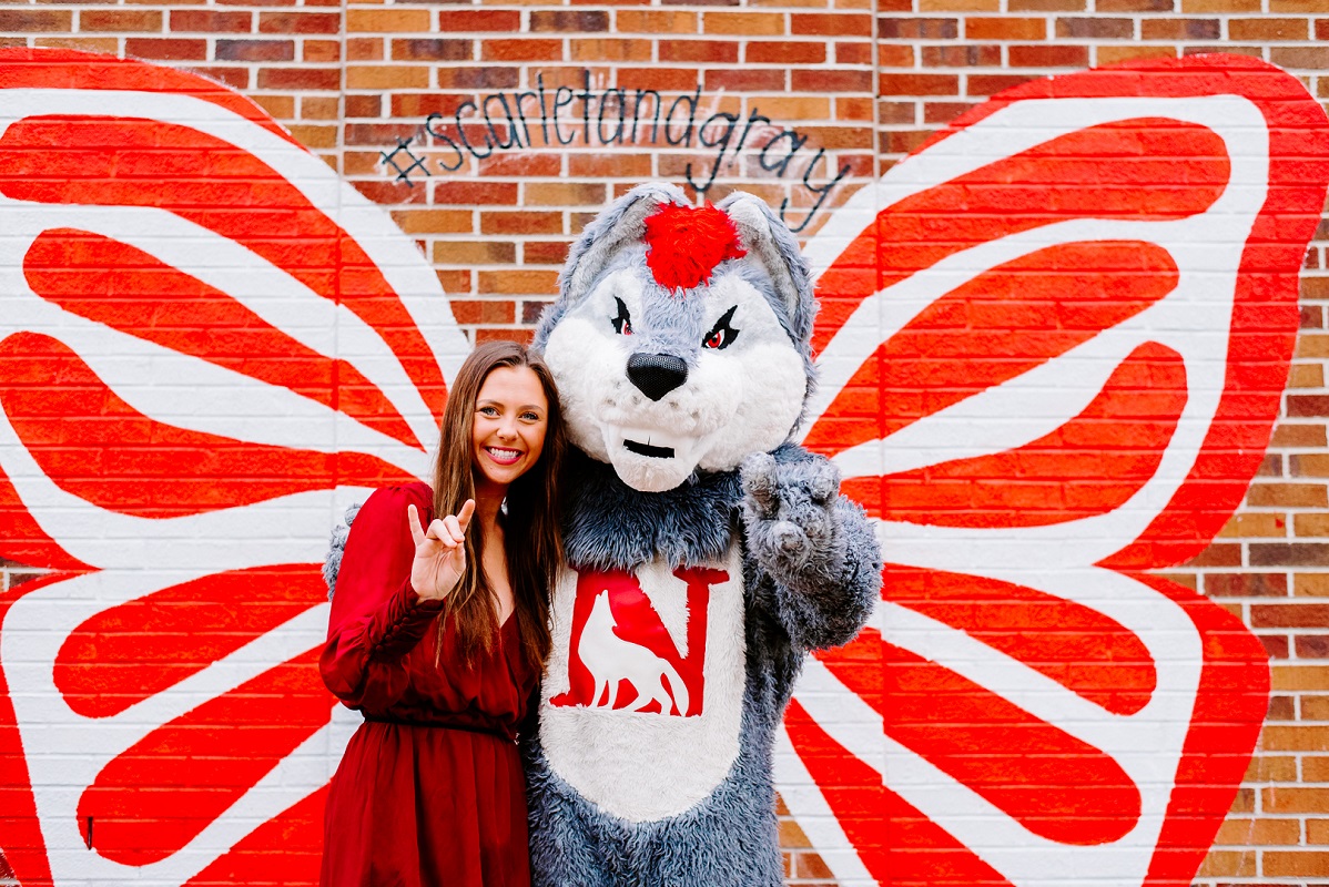 Female student stands with the wolf mascot named Scar
