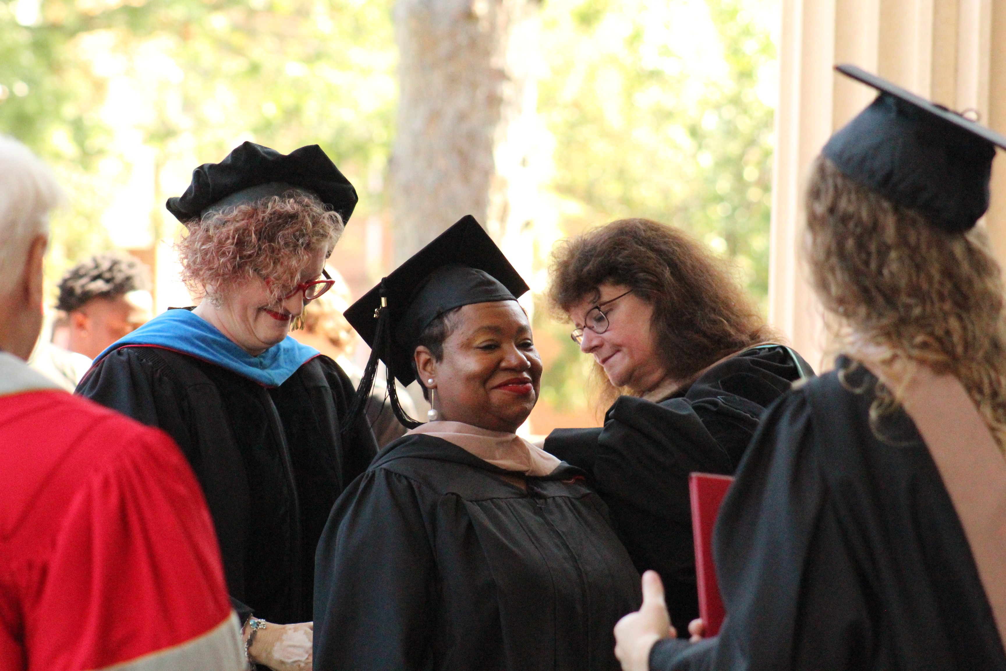 A female Newberry College master's graduate receives her hood at graduation