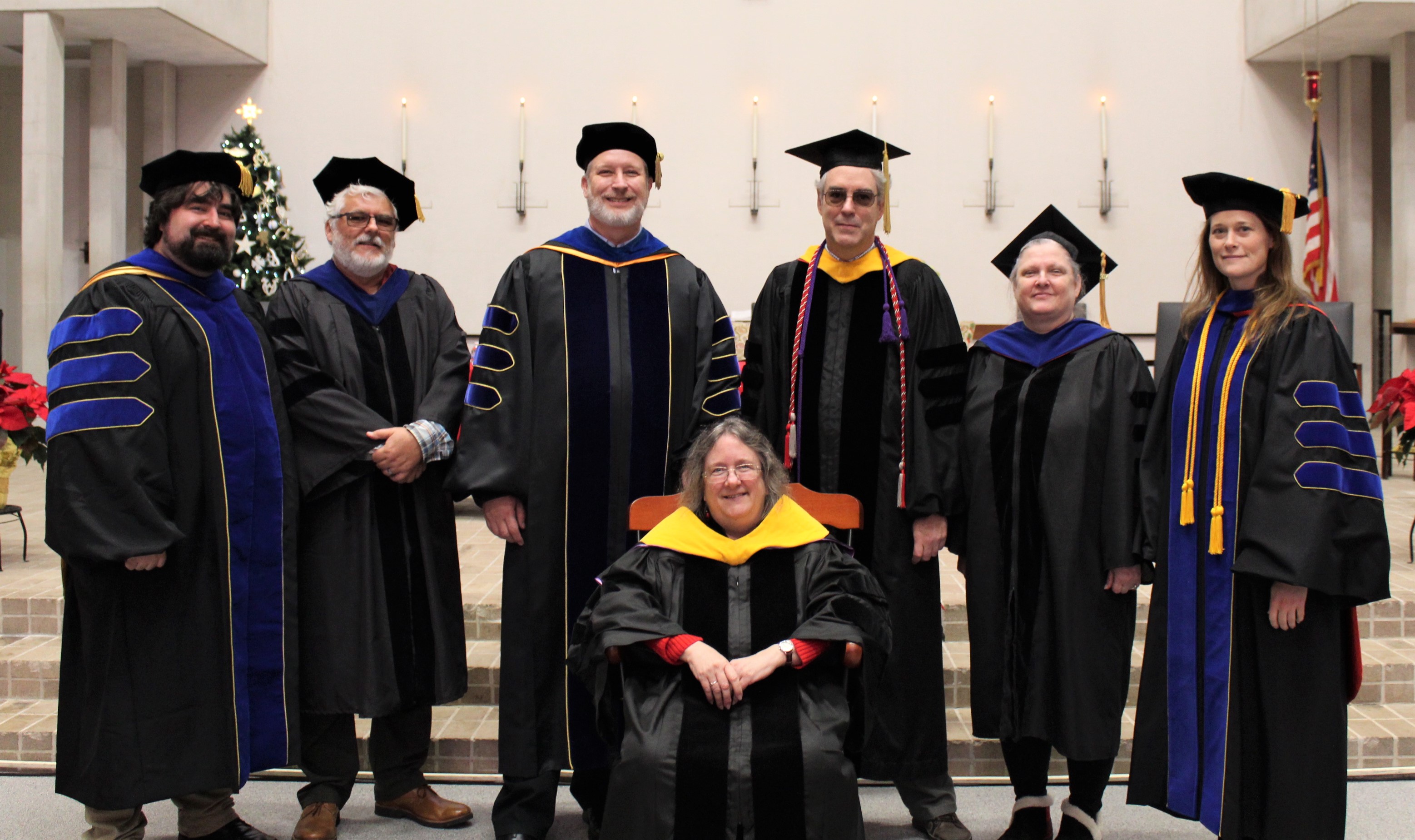 Dr. Christina McCartha sits in a rocking chair surrounded by professors of biology and chemistry