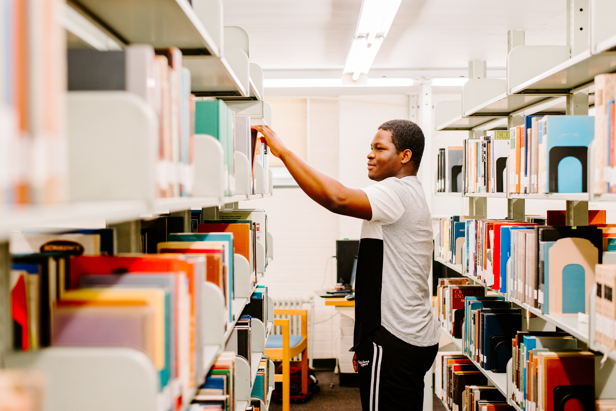Male student reaching for a book in the library
