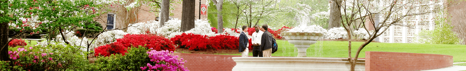 3 males talking on campus by fountain